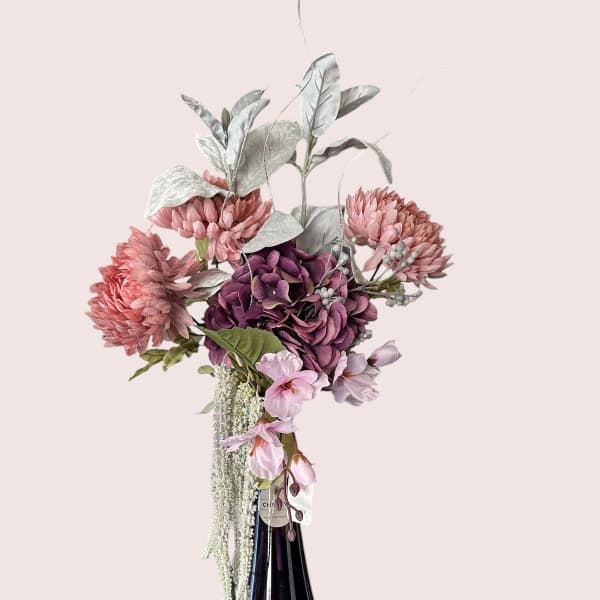 Pink and purple floral arrangement in a dark glass vase