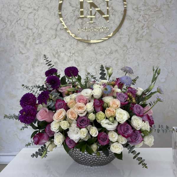 Large mixed bouquet of roses and purple blooms in a silver vase