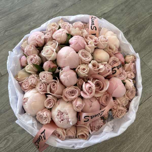 Large bouquet of pale pink roses and peonies wrapped in white paper