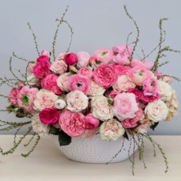 Low centerpiece of pink and white blooms in a white ceramic bowl
