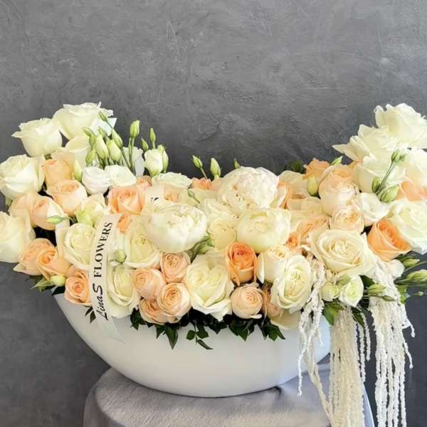 Cream and peach roses arranged in a white bowl-shaped vase