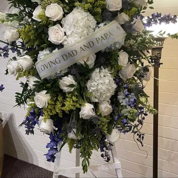 Large white and blue funeral spray with roses and hydrangeas
