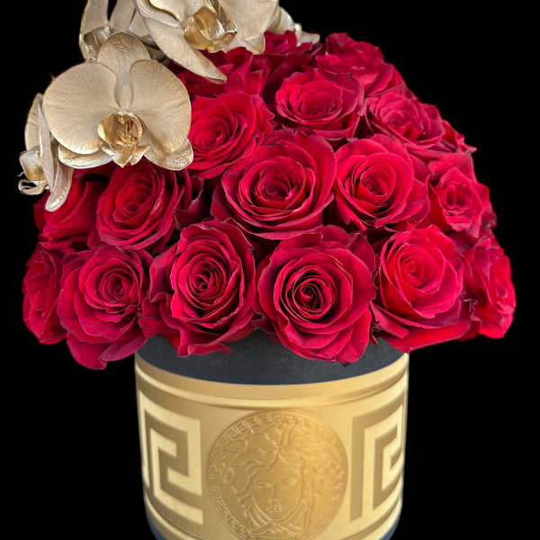 Red roses arranged in a gold box with pale orchids