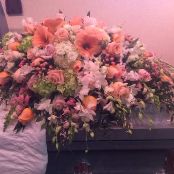 Large pink and peach floral casket spray with roses and lilies