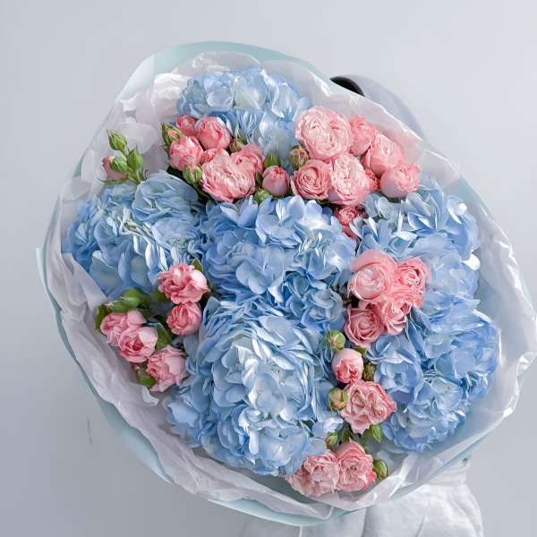 Bouquet of blue hydrangeas and pink roses wrapped in white paper