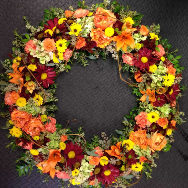 Heart-shaped floral wreath with orange, yellow, and burgundy blooms