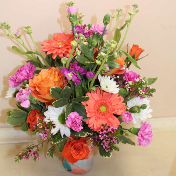 Mixed bouquet of orange, pink, and white flowers in a painted vase