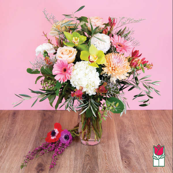 Mixed bouquet in a clear glass vase with pink, white, and peach blooms