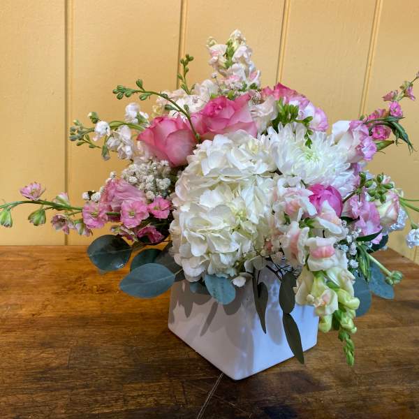 Pink and white floral arrangement in a white square vase