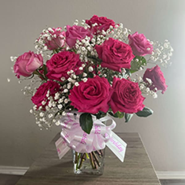 Bouquet of pink roses and baby's breath in a glass vase with a ribbon