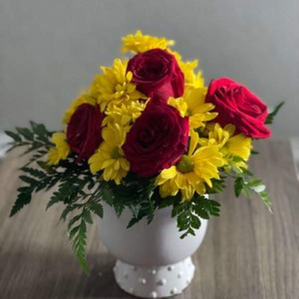 Red roses and yellow daisies in a white vase