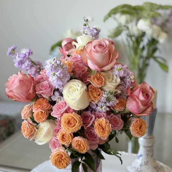 Bouquet of pink, peach, and white roses in a metallic vase