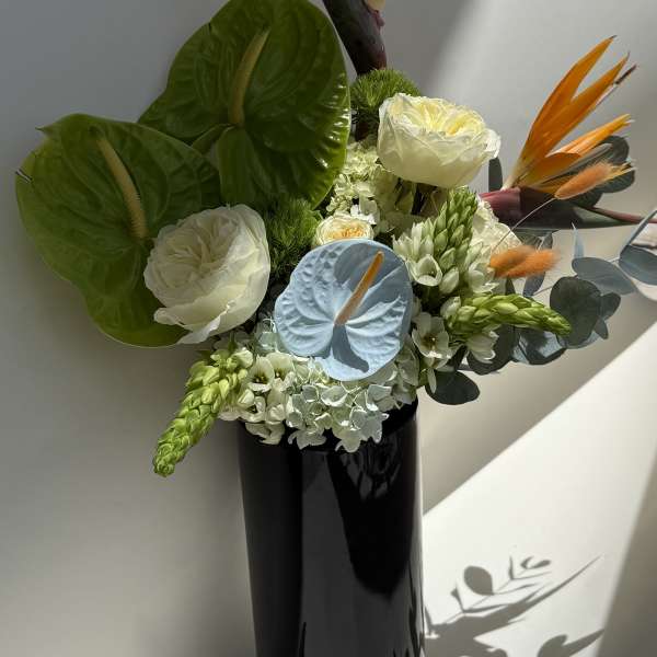 Tropical bouquet with white blooms in a black vase