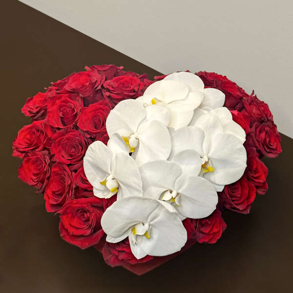 Heart-shaped arrangement of red roses with white orchids