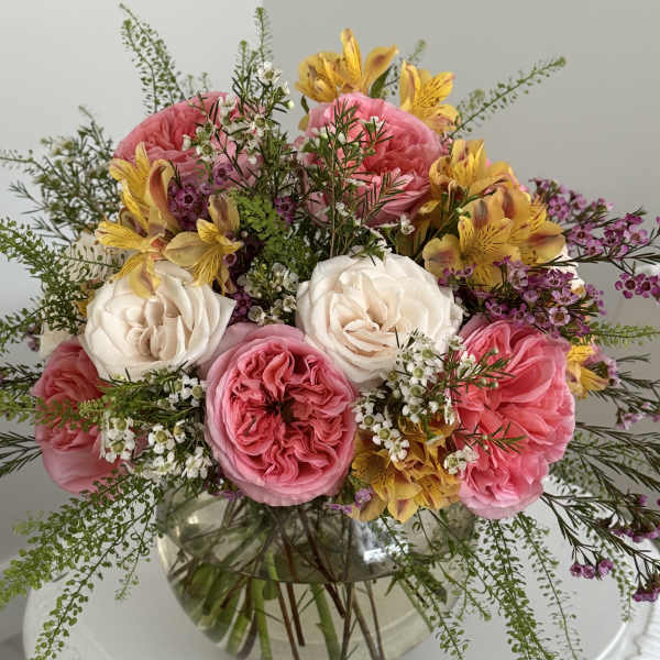 Pink and white roses with yellow flowers in a glass vase