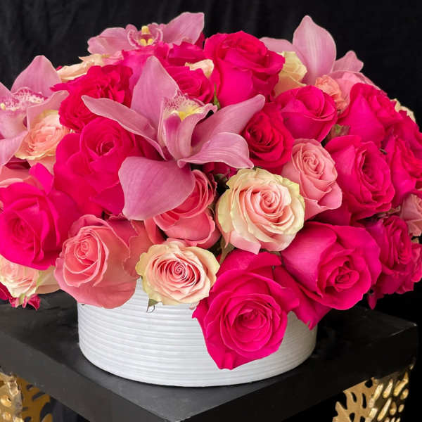 Pink and cream roses with orchid blooms in a white round vase