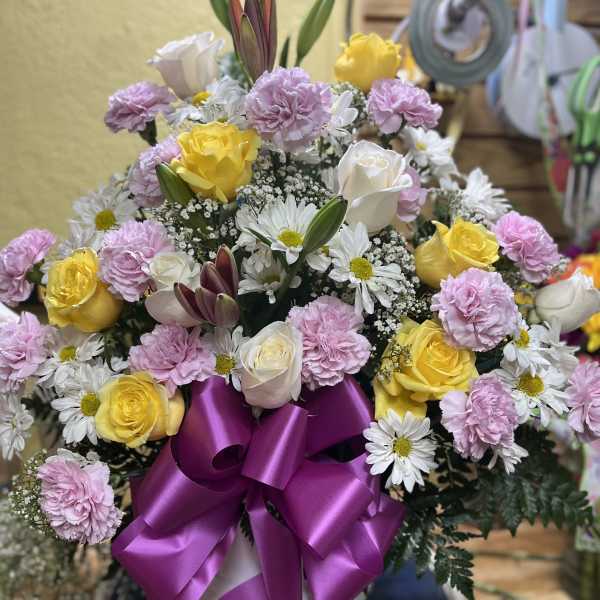 Bouquet of yellow and white roses with pink carnations and daisies in a vase