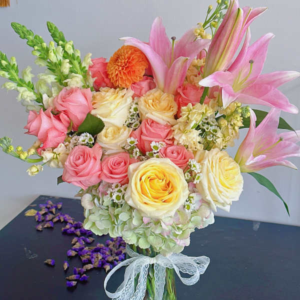 Bouquet of pink and yellow roses with pink lilies in a glass vase