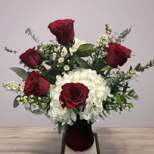Red roses and white hydrangeas in a dark vase