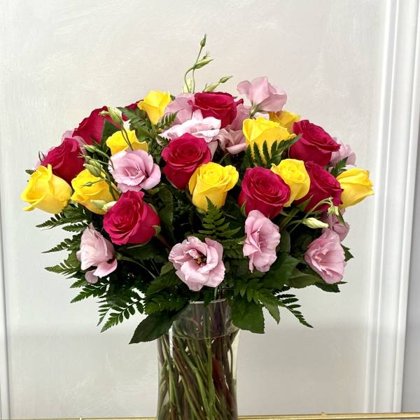Bouquet of pink and yellow roses in a clear glass vase