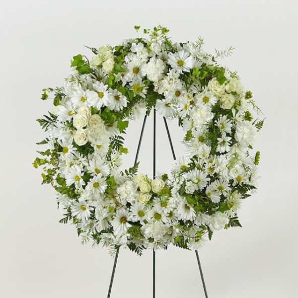 White floral wreath on a black stand