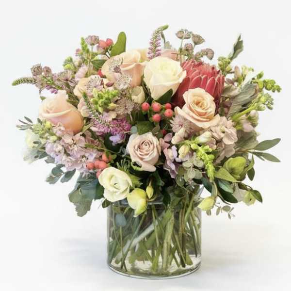 Mixed bouquet of roses and assorted flowers in a clear glass vase