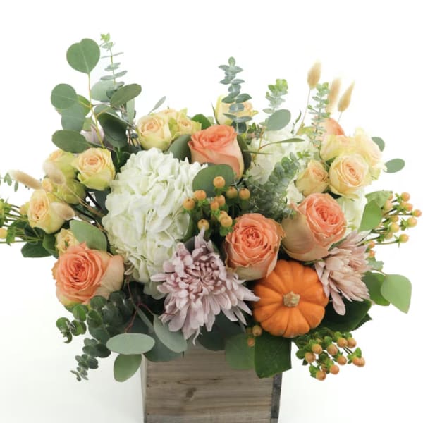 Mixed bouquet in a wooden box with peach roses, white hydrangea, and a small pumpkin