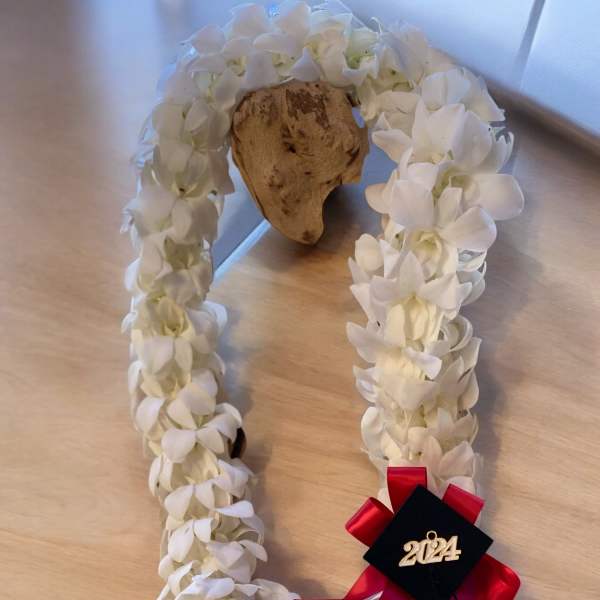 White flower lei with a red ribbon and 2024 charm