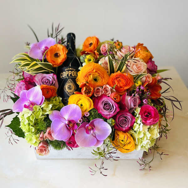 Mixed floral arrangement with orchids, roses, and ranunculus in a white box