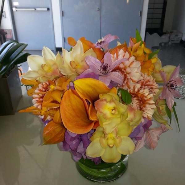 Bouquet of orange, yellow, pink, and purple flowers in a glass vase