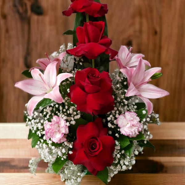 Red roses with pink lilies and carnations in a tiered arrangement