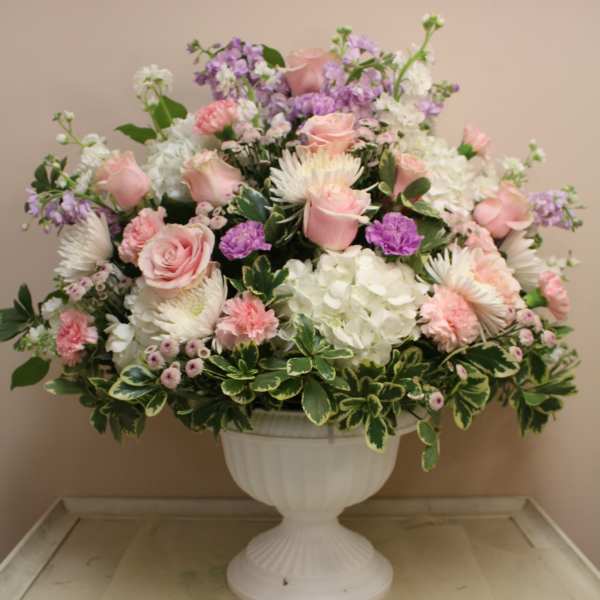 Pink and white floral arrangement in a white urn vase