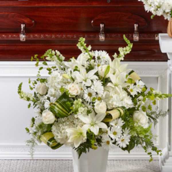White floral funeral arrangement in a white vase