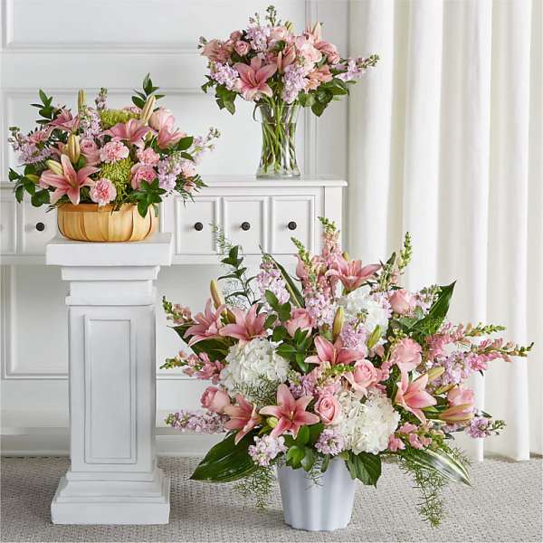 Three pink floral arrangements in vases and a pumpkin-shaped container