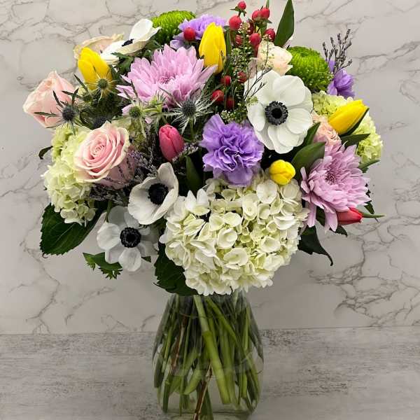 Mixed bouquet of pastel flowers in a clear glass vase