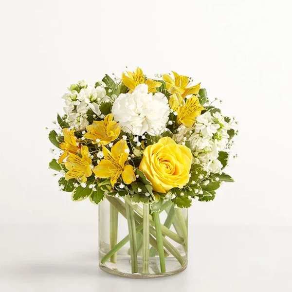 Yellow and white flower arrangement in a clear glass vase