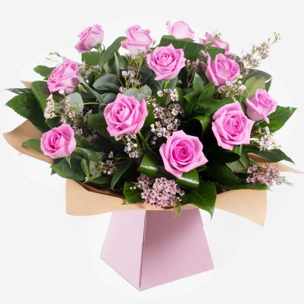 Pink roses arranged in a pink gift box with small filler flowers