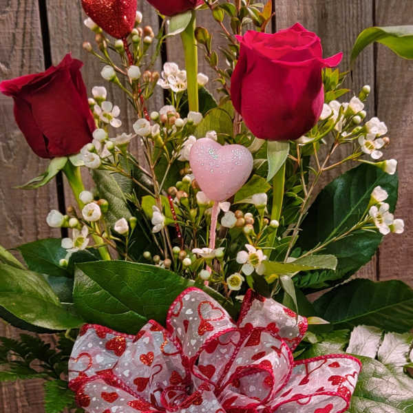 Red roses in a glass vase with a heart ribbon