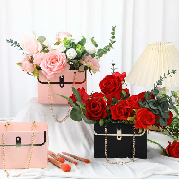 Pink and red rose arrangements in handbag-shaped boxes with a lamp and makeup brushes