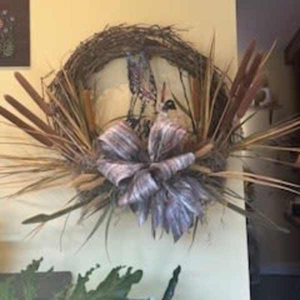 Decorative wreath with a large striped bow and dried grasses