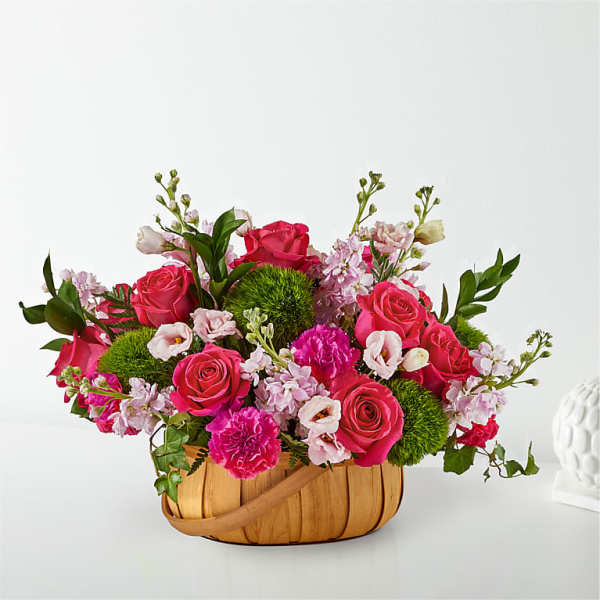 Pink roses and carnations in a woven basket with green pom-pom flowers