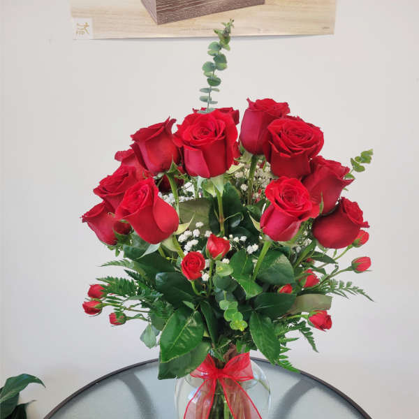 Red roses arranged in a clear glass vase with a red ribbon