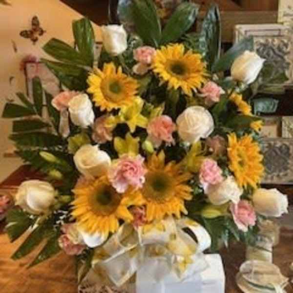 Bouquet of sunflowers, white roses, and pink carnations with a ribbon
