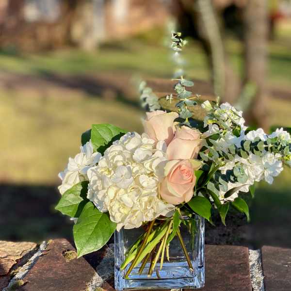 Blush roses and white hydrangeas in a clear glass vase
