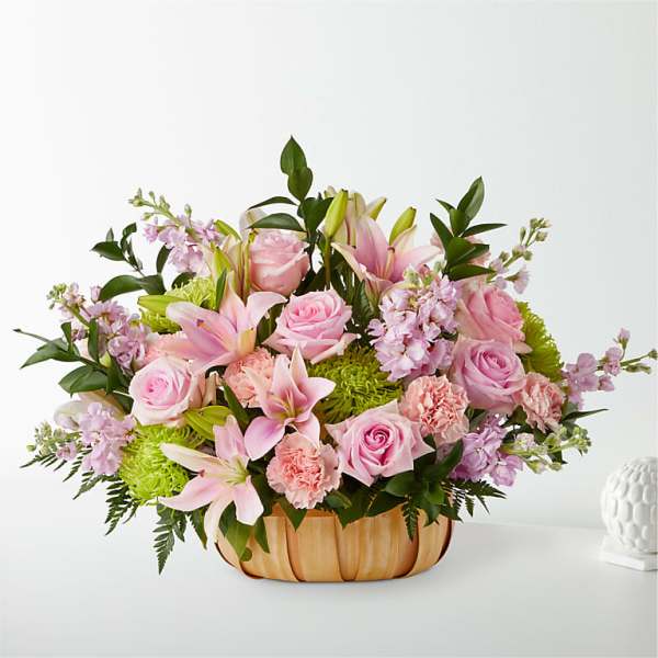 Pink roses and lilies arranged in a low wooden basket