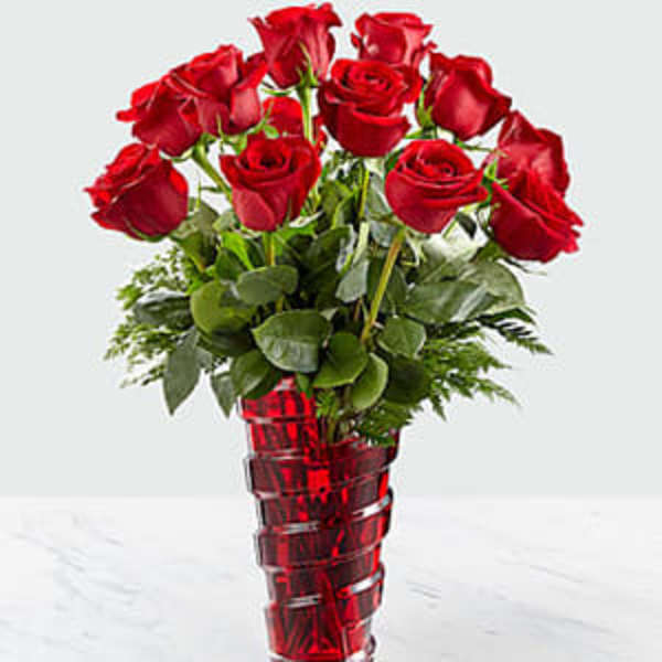 Red roses arranged in a tall red glass vase