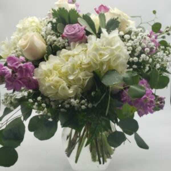 Bouquet of white and purple flowers with greenery in a vase