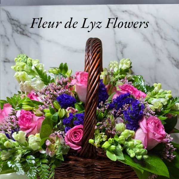 Pink and white flowers arranged in a wicker basket