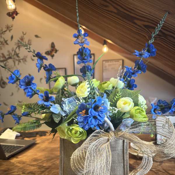 Blue and lime floral arrangement in a burlap box with a sheer bow