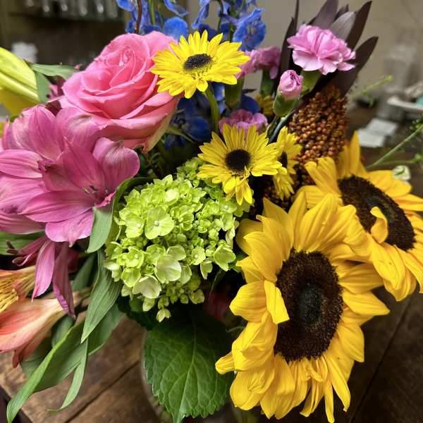 Mixed bouquet with sunflowers, pink roses, and blue delphinium